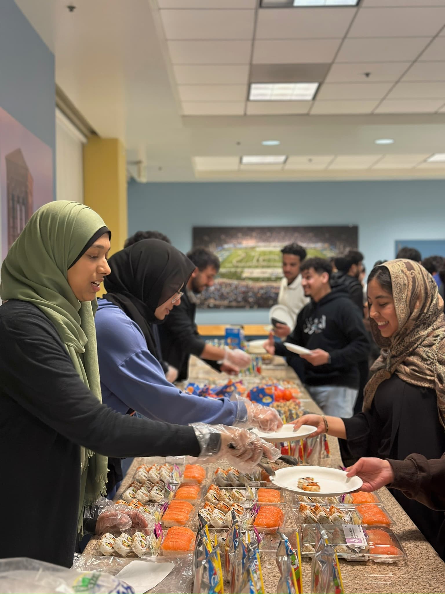 Muslim women (left) serving food such as sushi to other students (right).